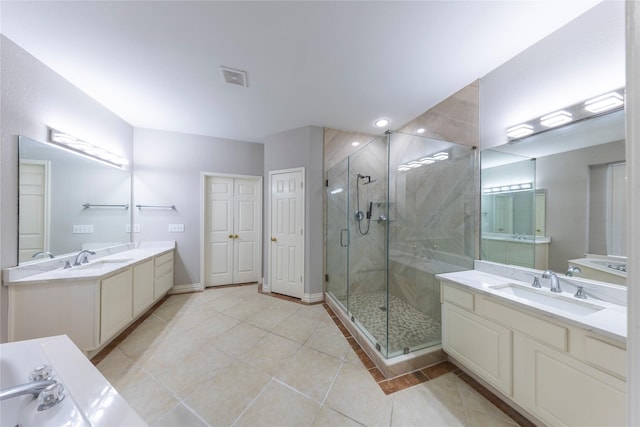 bathroom featuring two vanities, a stall shower, tile patterned flooring, and a sink