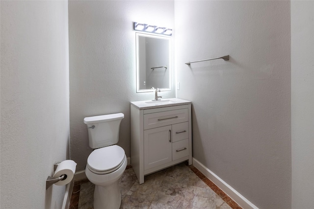 half bath with baseboards, vanity, and toilet