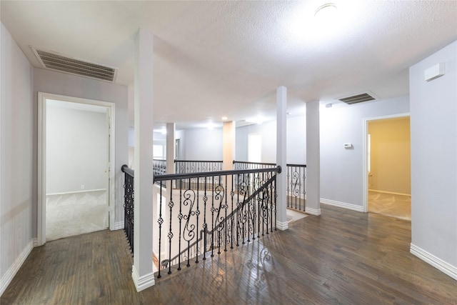 corridor featuring baseboards, visible vents, an upstairs landing, and wood finished floors