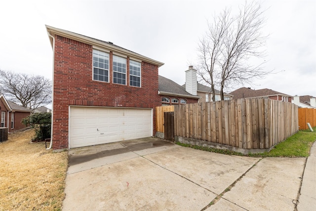 view of front facade featuring driveway, an attached garage, fence, and brick siding