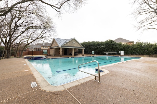 view of pool featuring an outbuilding, a pool with connected hot tub, a patio area, and fence