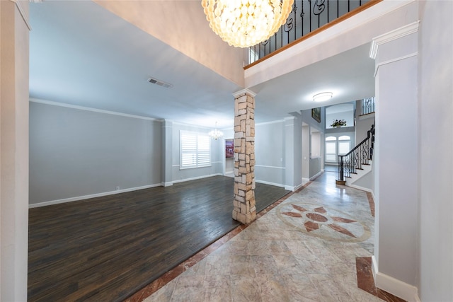 foyer entrance featuring a notable chandelier, visible vents, stairway, ornamental molding, and ornate columns