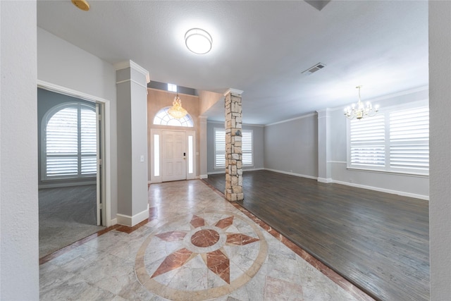 foyer with ornate columns, visible vents, a wealth of natural light, and ornamental molding