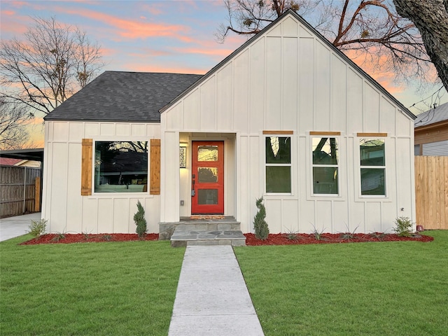 modern farmhouse style home with board and batten siding, a yard, a shingled roof, and fence