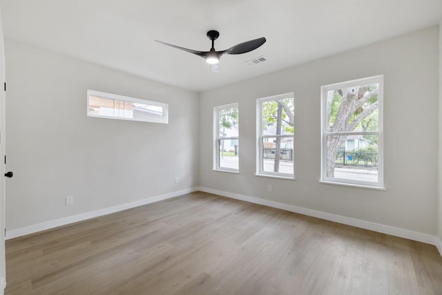 unfurnished room with baseboards, light wood-type flooring, a ceiling fan, and a healthy amount of sunlight