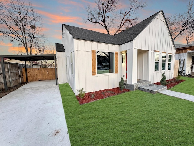 modern inspired farmhouse featuring a shingled roof, board and batten siding, a front yard, and fence