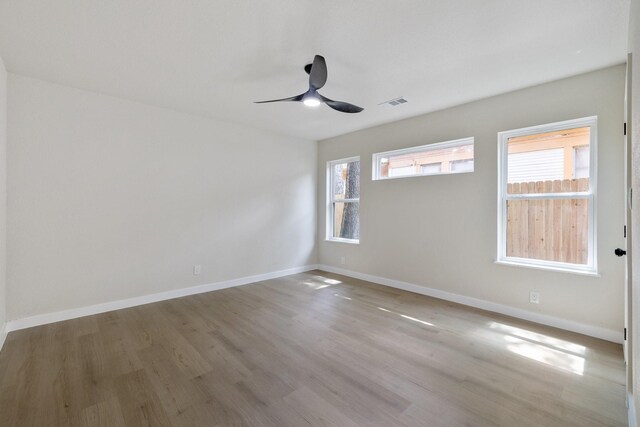 unfurnished room with baseboards, plenty of natural light, visible vents, and wood finished floors