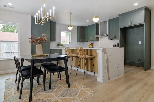 kitchen with wall chimney range hood, light wood-type flooring, visible vents, and recessed lighting