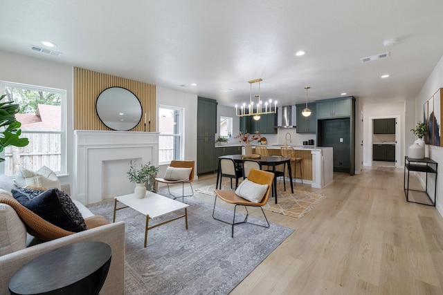 living area with a wealth of natural light, a fireplace, visible vents, and light wood-style floors