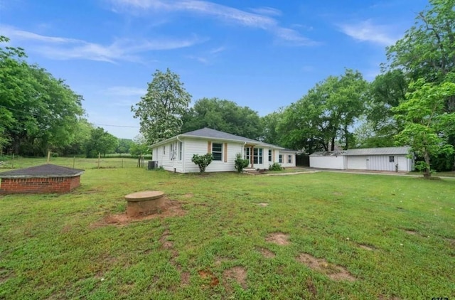 rear view of property with a lawn, an outdoor structure, and fence