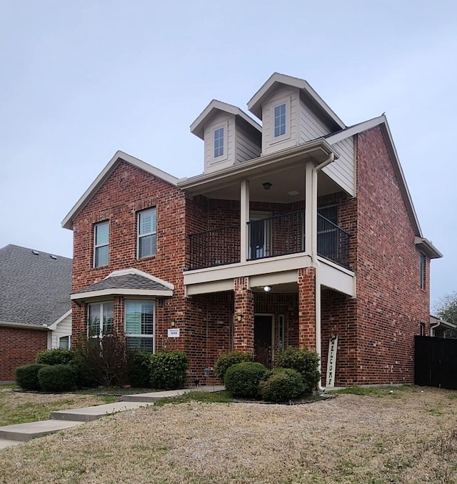 traditional home featuring a balcony and brick siding