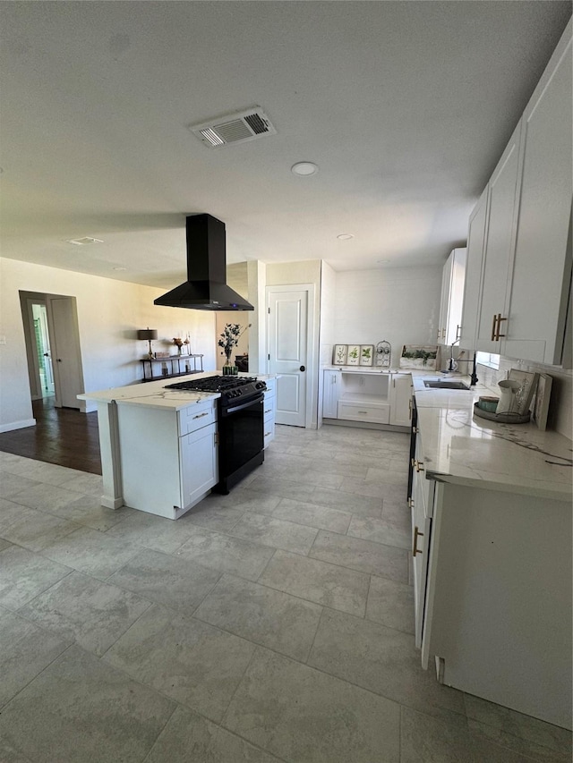 kitchen featuring a sink, visible vents, white cabinetry, range hood, and black gas range oven