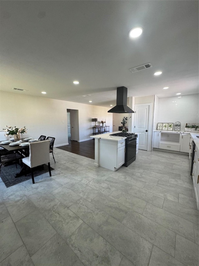 kitchen with recessed lighting, visible vents, white cabinets, gas stove, and island exhaust hood