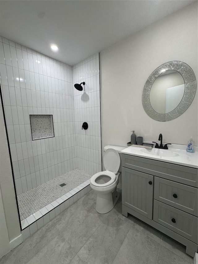 full bath with toilet, a tile shower, and vanity