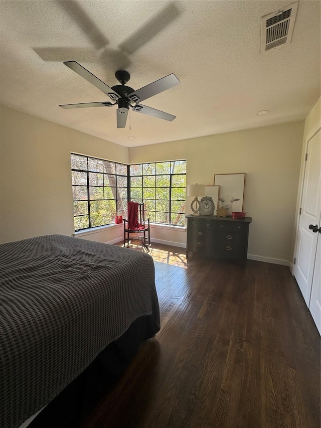 bedroom featuring a textured ceiling, ceiling fan, wood finished floors, visible vents, and baseboards