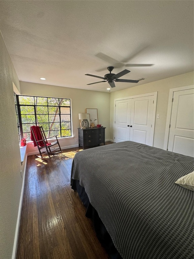 bedroom with dark wood-style floors, a textured ceiling, a ceiling fan, and baseboards