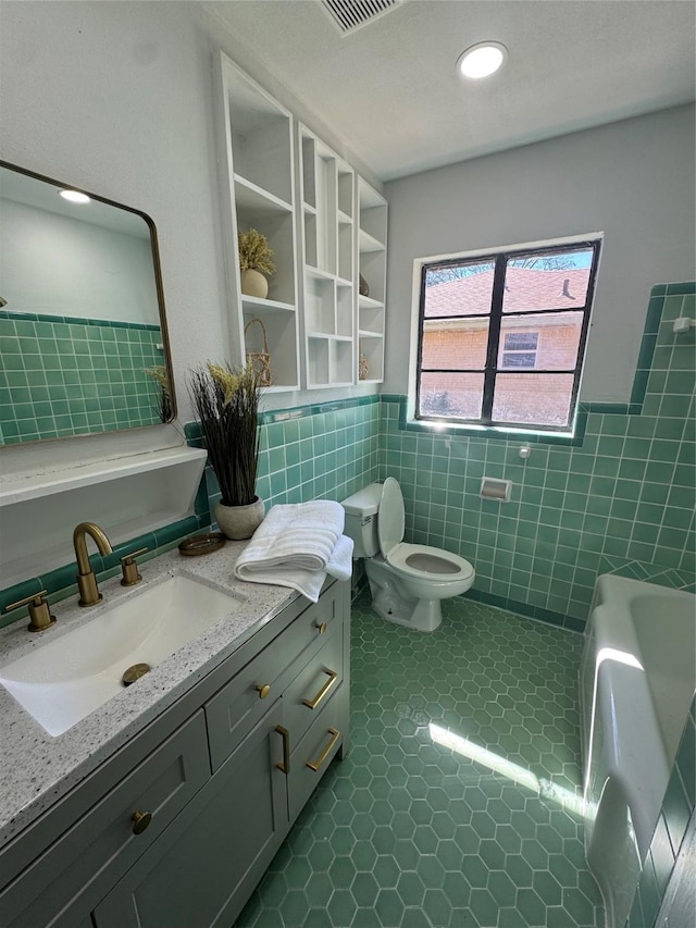 bathroom with toilet, wainscoting, tile patterned flooring, and tile walls