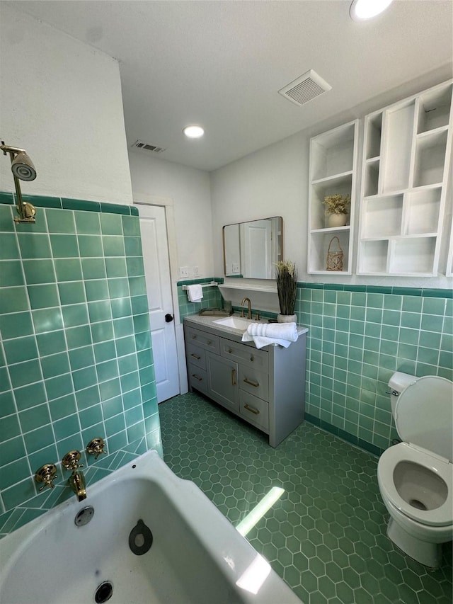 full bathroom featuring toilet, a bathtub, visible vents, and tile walls