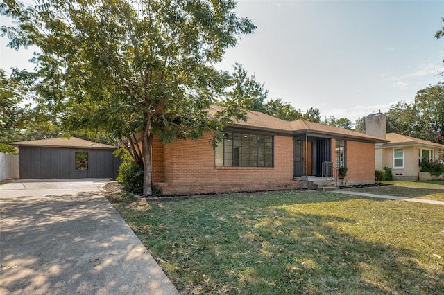 view of front facade with concrete driveway, brick siding, a front lawn, and an outdoor structure