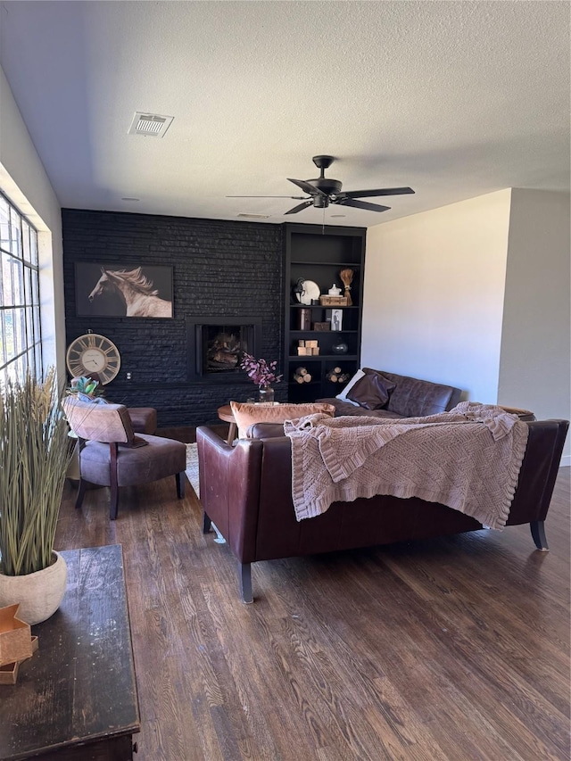 bedroom with visible vents, a ceiling fan, wood finished floors, a textured ceiling, and a fireplace