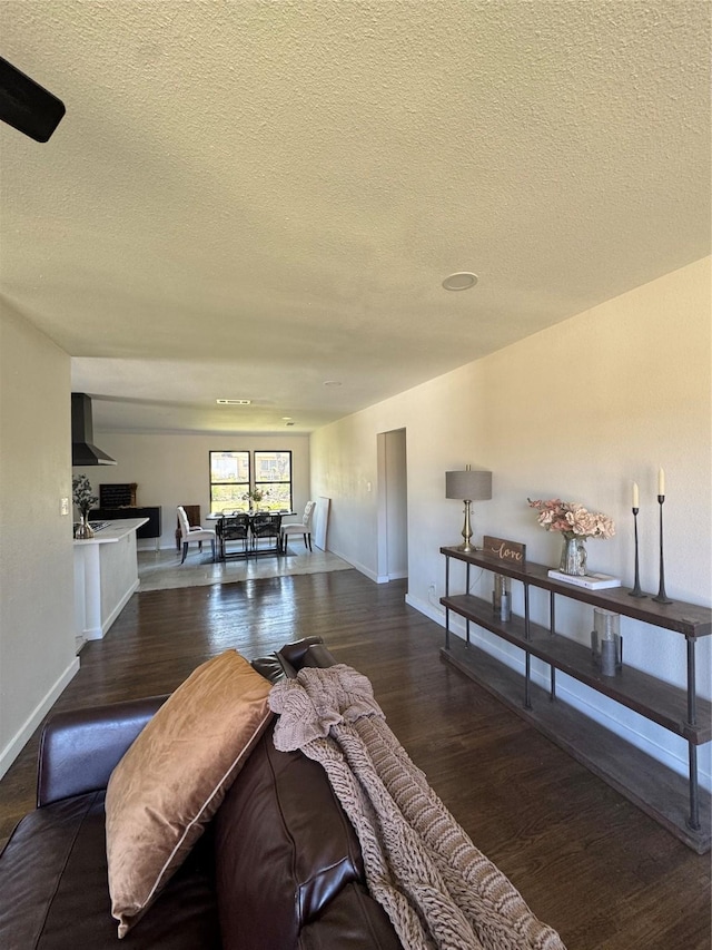 living area with a textured ceiling, baseboards, and wood finished floors