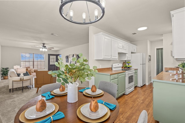 dining space with ceiling fan with notable chandelier, visible vents, and light wood finished floors