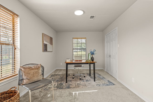 office with visible vents, baseboards, and light colored carpet