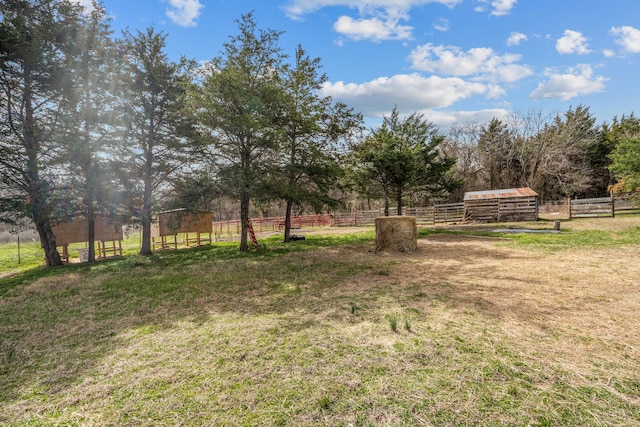 view of yard with a rural view, an outbuilding, and fence