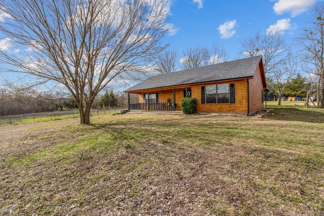 view of front of home featuring roof with shingles, covered porch, a front yard, and fence