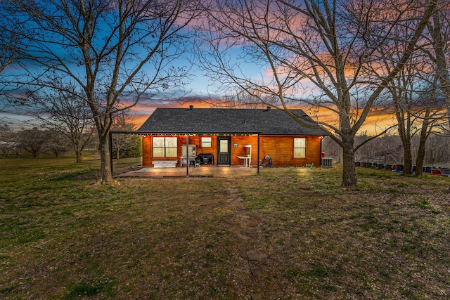 rear view of house with cooling unit, a lawn, and a patio area