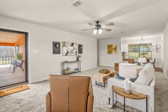 living area with ceiling fan with notable chandelier, light colored carpet, visible vents, and baseboards