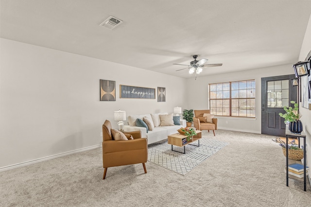 living area featuring visible vents, light colored carpet, a ceiling fan, and baseboards