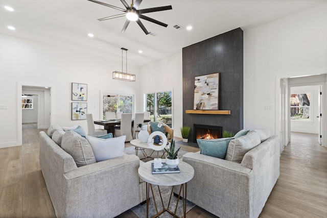 300 Covey Ln, Mckinney, TX 75071 - living room with visible vents, a large fireplace, light wood-style flooring, a high ceiling, and a ceiling fan