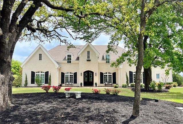 french country style house with stucco siding and a front yard