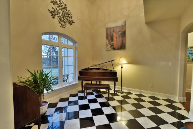 sitting room featuring arched walkways, baseboards, and tile patterned floors