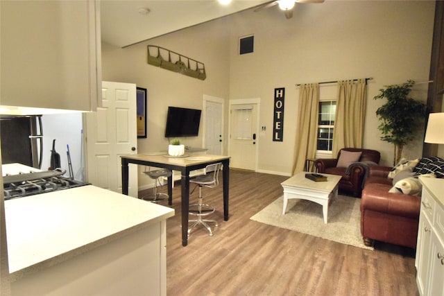 living room with visible vents, high vaulted ceiling, light wood-type flooring, and a ceiling fan