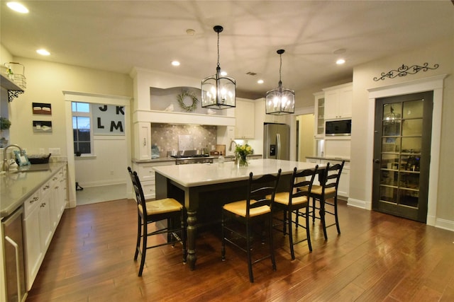 kitchen with stainless steel fridge, white cabinetry, a breakfast bar, and decorative backsplash