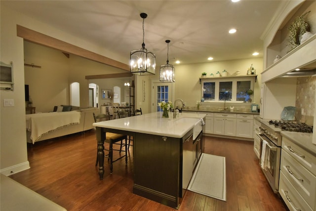 kitchen featuring a center island with sink, white cabinets, dark wood finished floors, a breakfast bar area, and high end stainless steel range oven