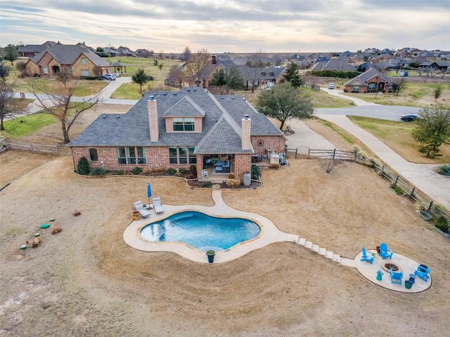 view of swimming pool featuring a patio area, fence, and a residential view