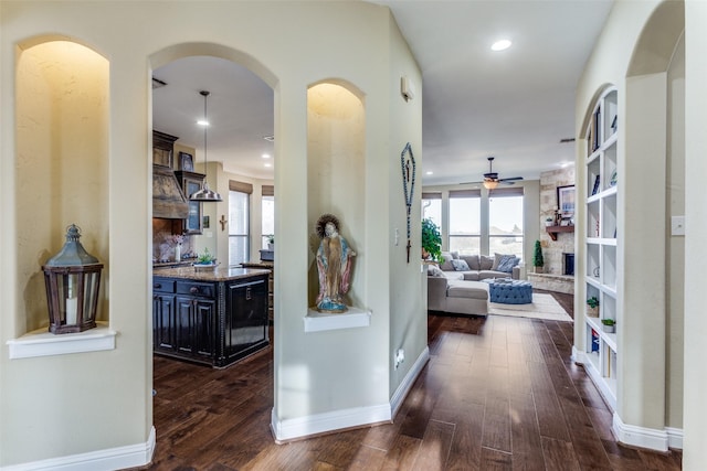 hall featuring arched walkways, dark wood-style flooring, baseboards, and recessed lighting