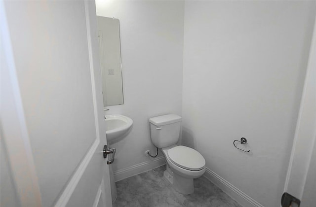 bathroom with a sink, toilet, and baseboards