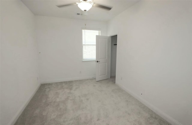 spare room with baseboards, ceiling fan, visible vents, and light colored carpet