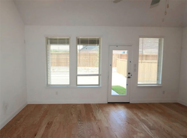 doorway with light wood-type flooring, ceiling fan, and baseboards