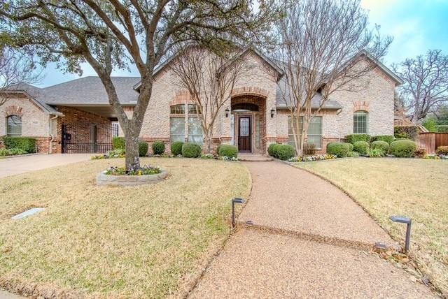 view of front of home featuring brick siding, fence, and a front lawn