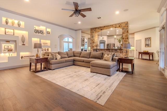 living area with arched walkways, crown molding, recessed lighting, visible vents, and light wood-style floors