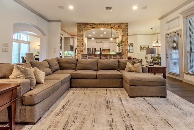 living area with visible vents, arched walkways, wood finished floors, crown molding, and recessed lighting