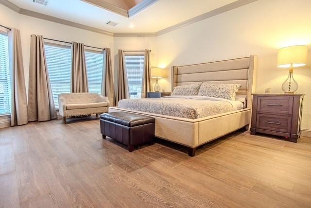 bedroom with light wood-style flooring, multiple windows, and ornamental molding