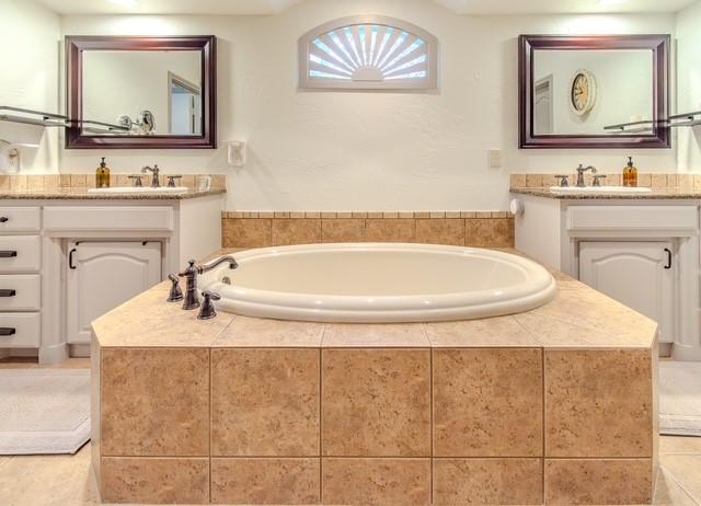 bathroom with two vanities, a sink, and a bath