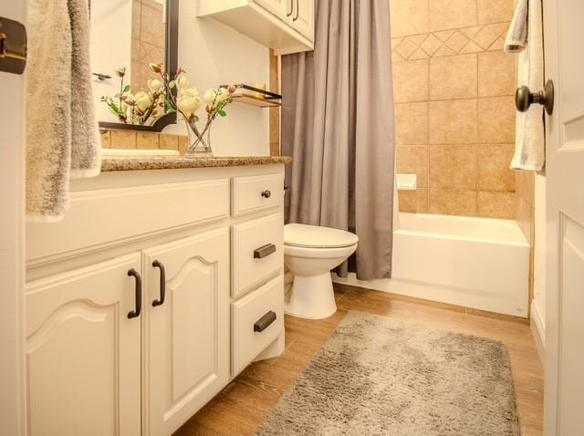 full bathroom with toilet, shower / bathtub combination with curtain, wood finished floors, and vanity