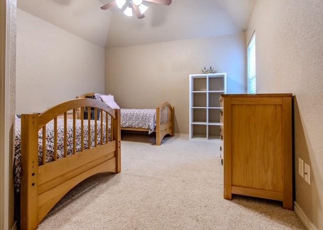 bedroom with lofted ceiling, ceiling fan, baseboards, and light colored carpet